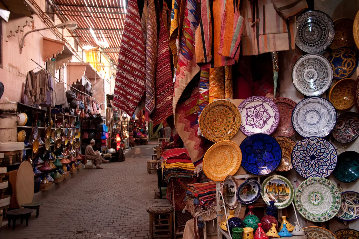 Berber rugs, ceramics and lamps displayed in a Marrakech souk alley